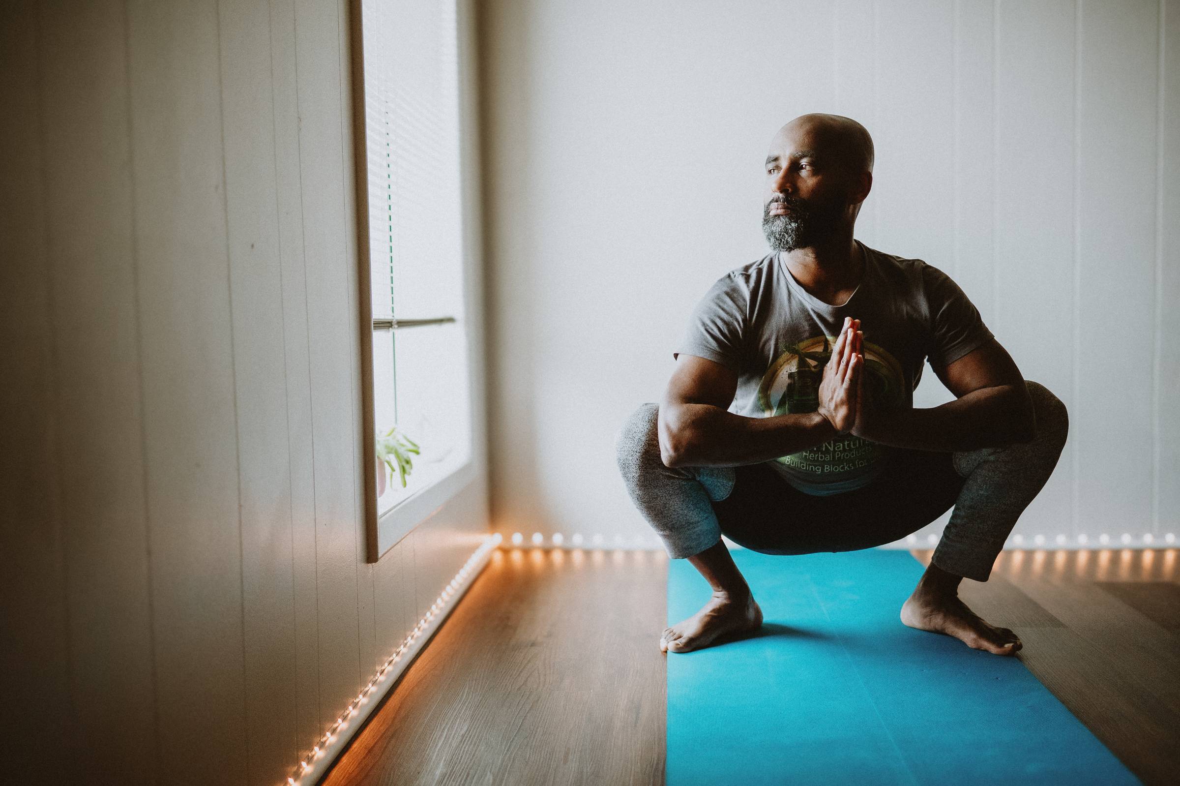 Man calmly practicing yoga in a studio while looking contemplatively out the window