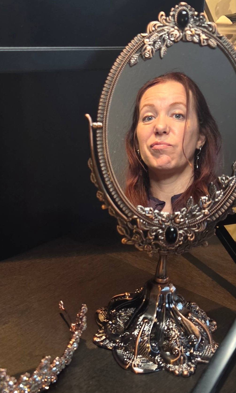 A woman's reflection in an ornate tabletop mirror