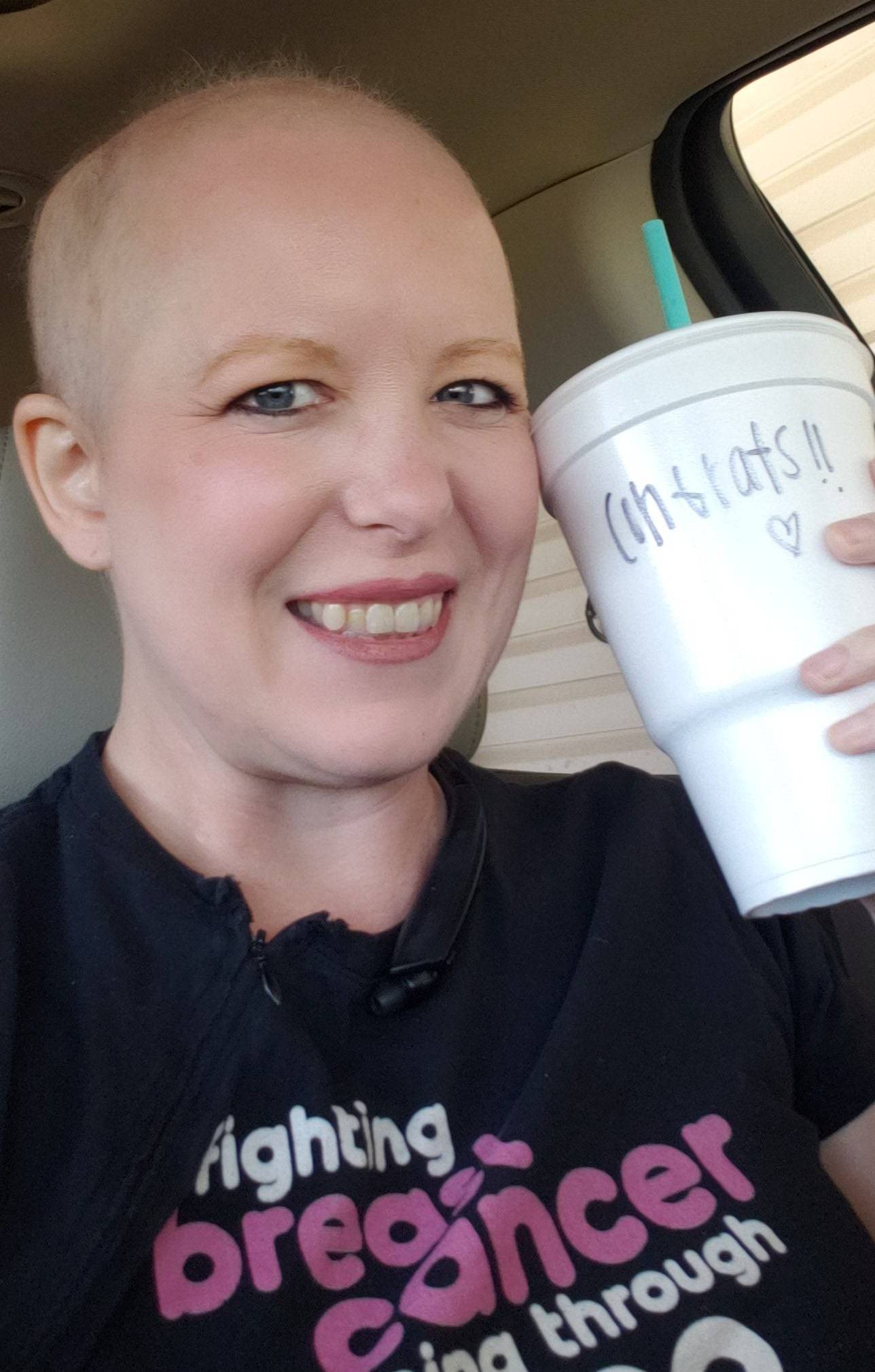 A smiling bald woman celebrating her last day of chemo