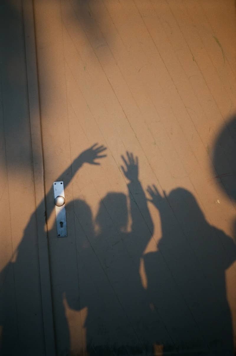 Shadows of three people with raised hands on a wall