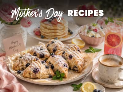 table laid with a variety of breakfast items -- scones, pancakes, fruit salad, coffee. text: Mother's Day Recipes