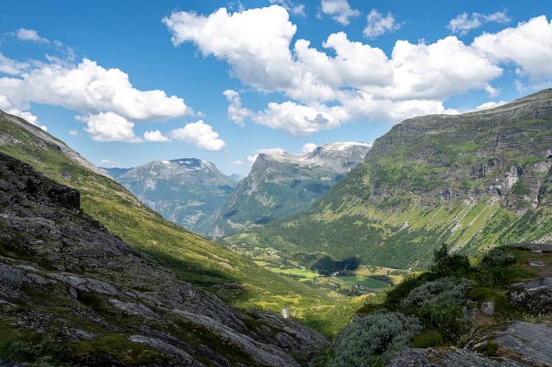 Mountains and valley bask under a sunny, cloudy sky.