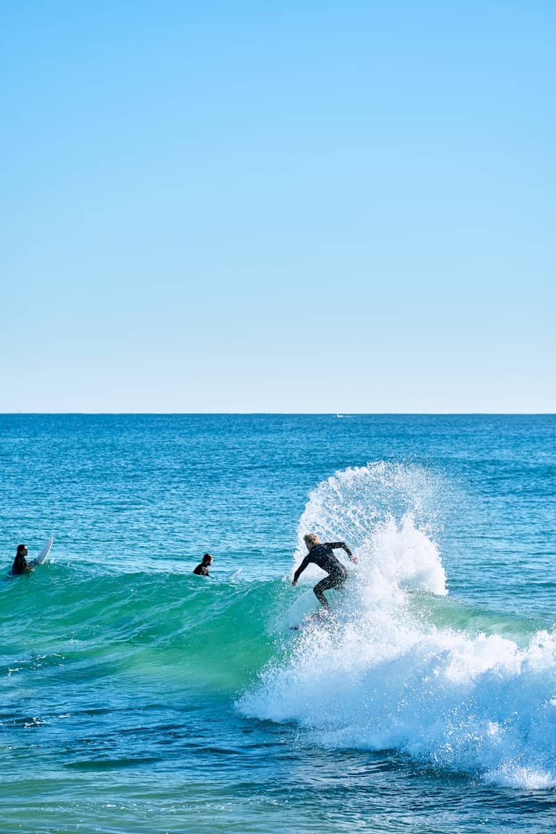 Surfer rides a wave with spray in the ocean.
