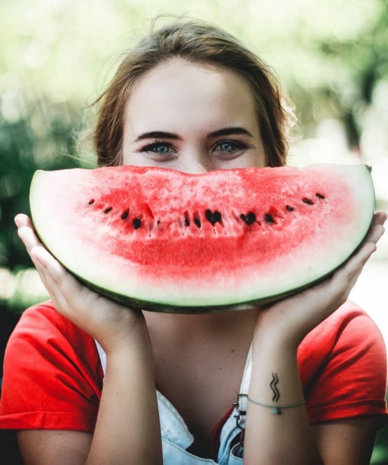 woman holding sliced watermelon
