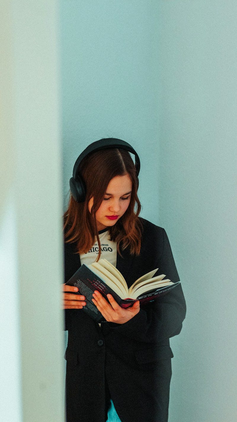 a woman wearing headphones is reading a book