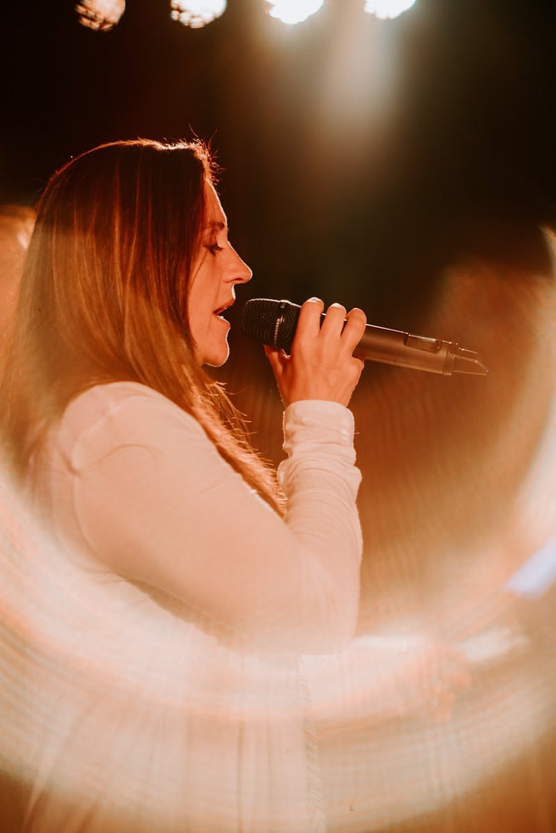 woman holding microphone while singing on stage