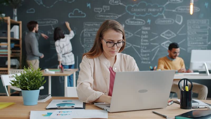 Woman working on laptop in busy modern office