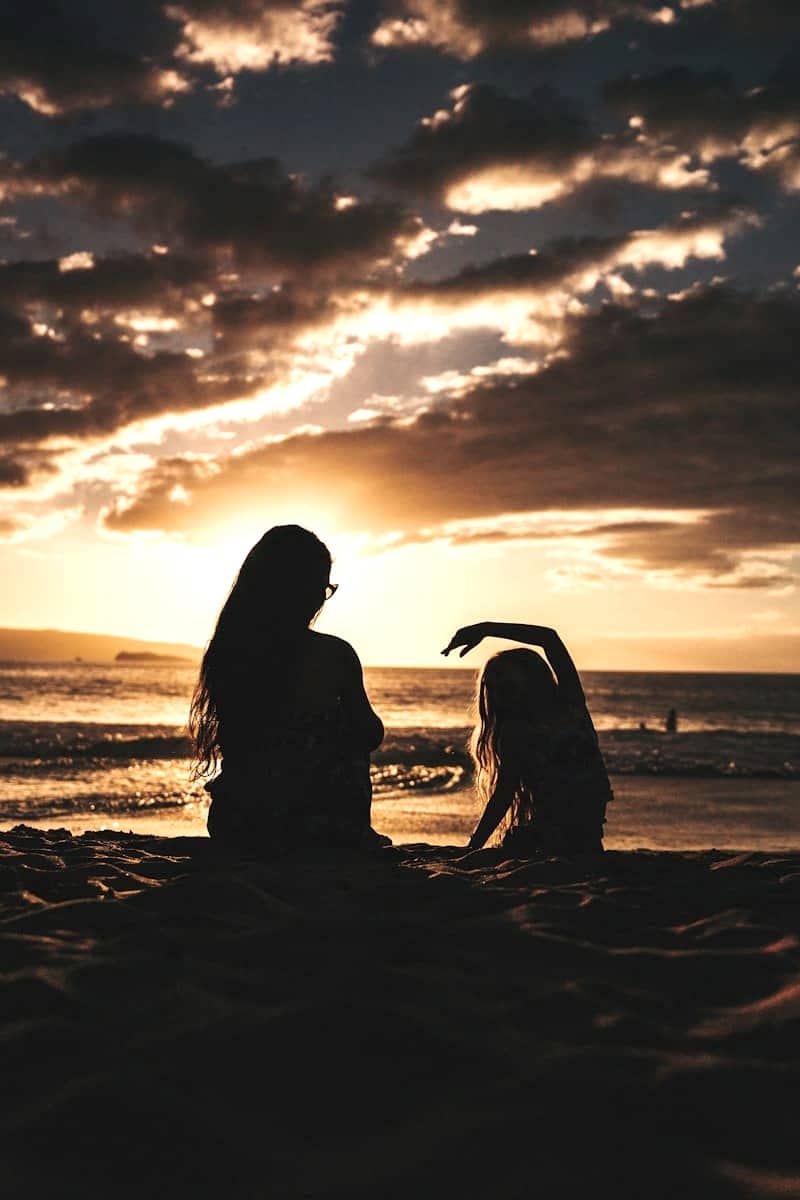 silhouette photo of woman and girl on shoreline