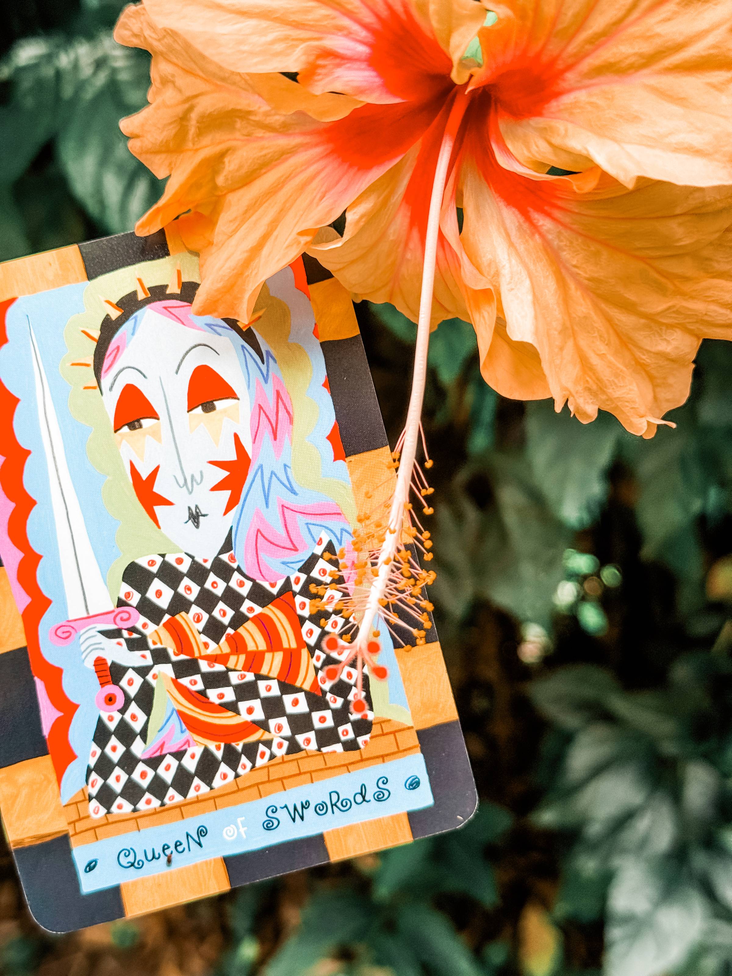 Queen of Swords card from Gentle Thrills Tarot with a hibiscus flower