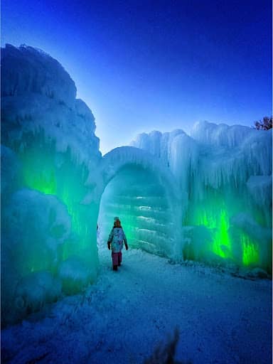 a kid walking through an ice tunnel at the Ice Castles