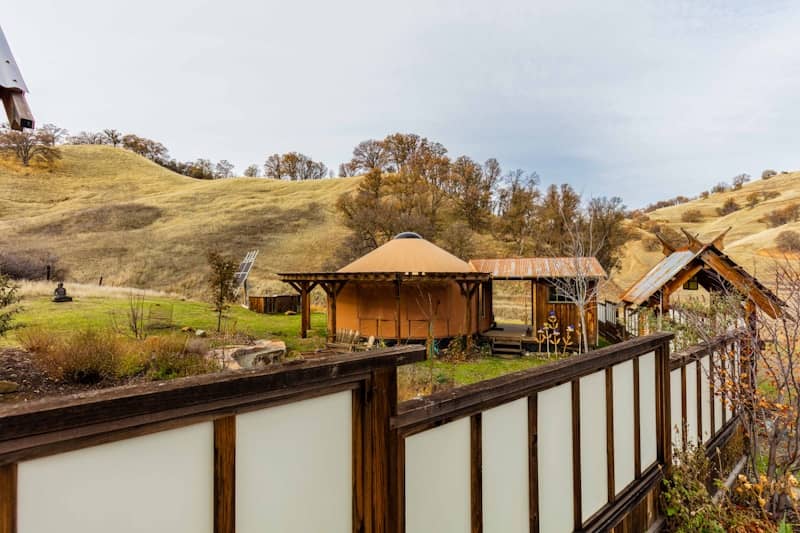 Wooden structures sit against a hilly landscape.