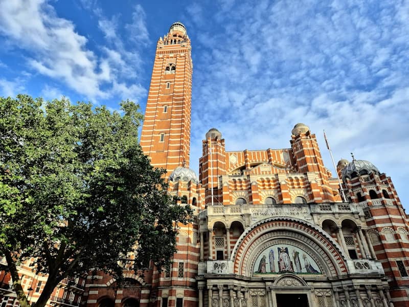 Grand brick cathedral with a tall tower under blue sky.