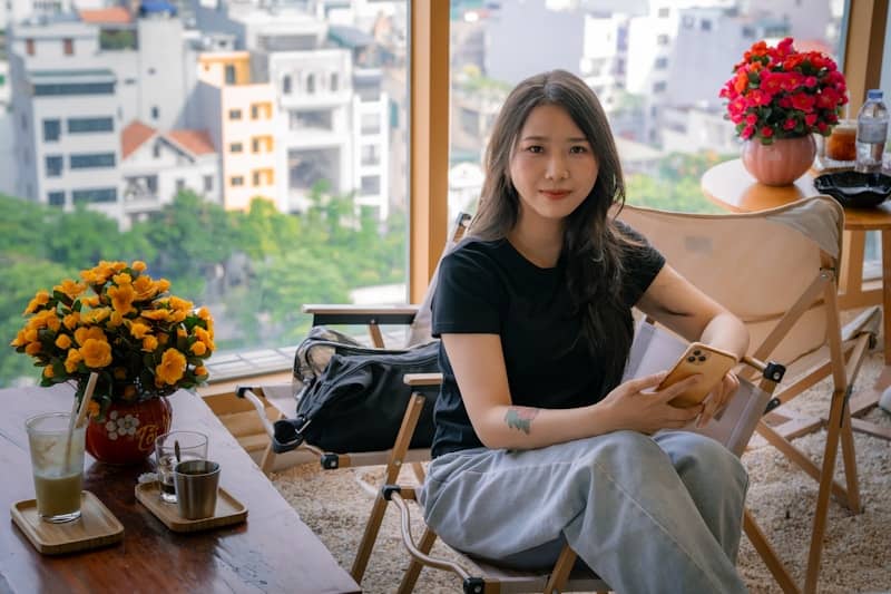 Smiling woman in cafe with flowers and city view.