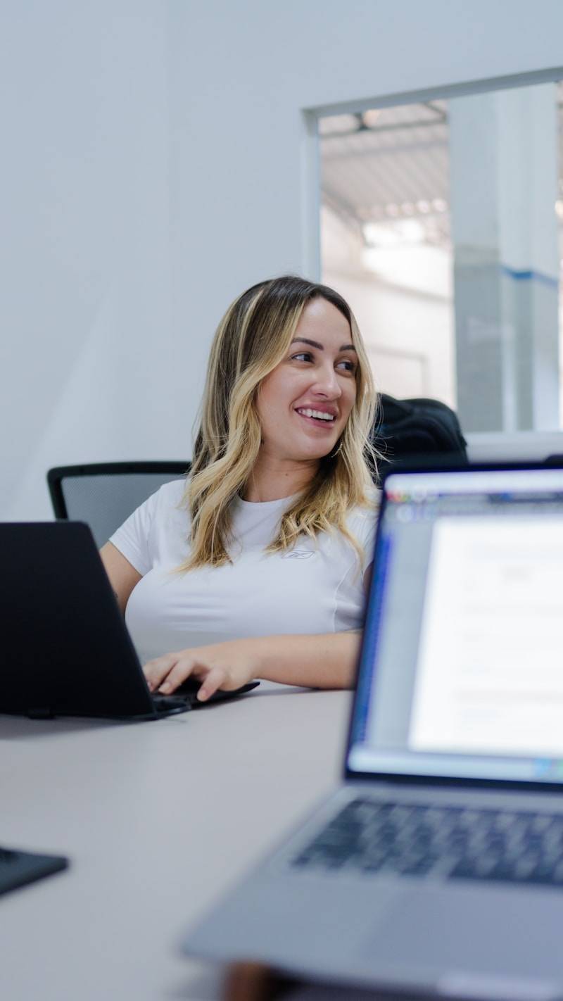 A woman smiles while working on her laptop.