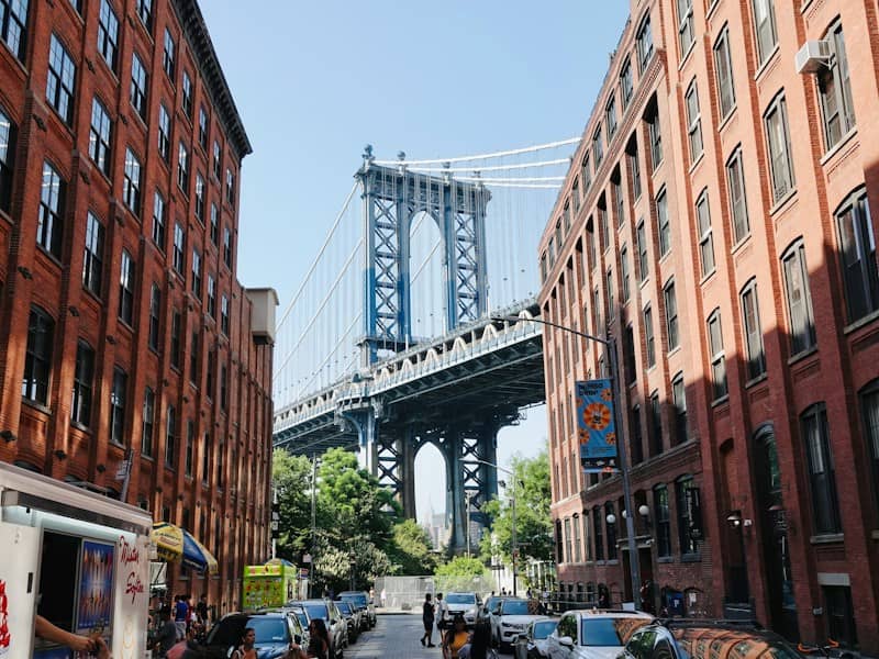 The Manhattan Bridge framed by red brick buildings on a street in New York
