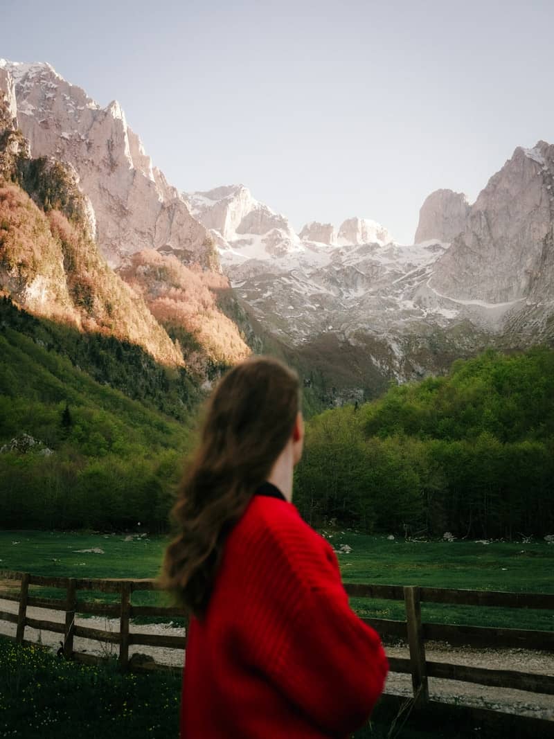 Woman gazes at mountains in a vibrant landscape.