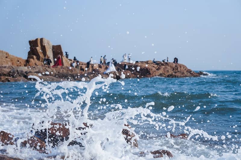 Waves crash against rocks near a shore.