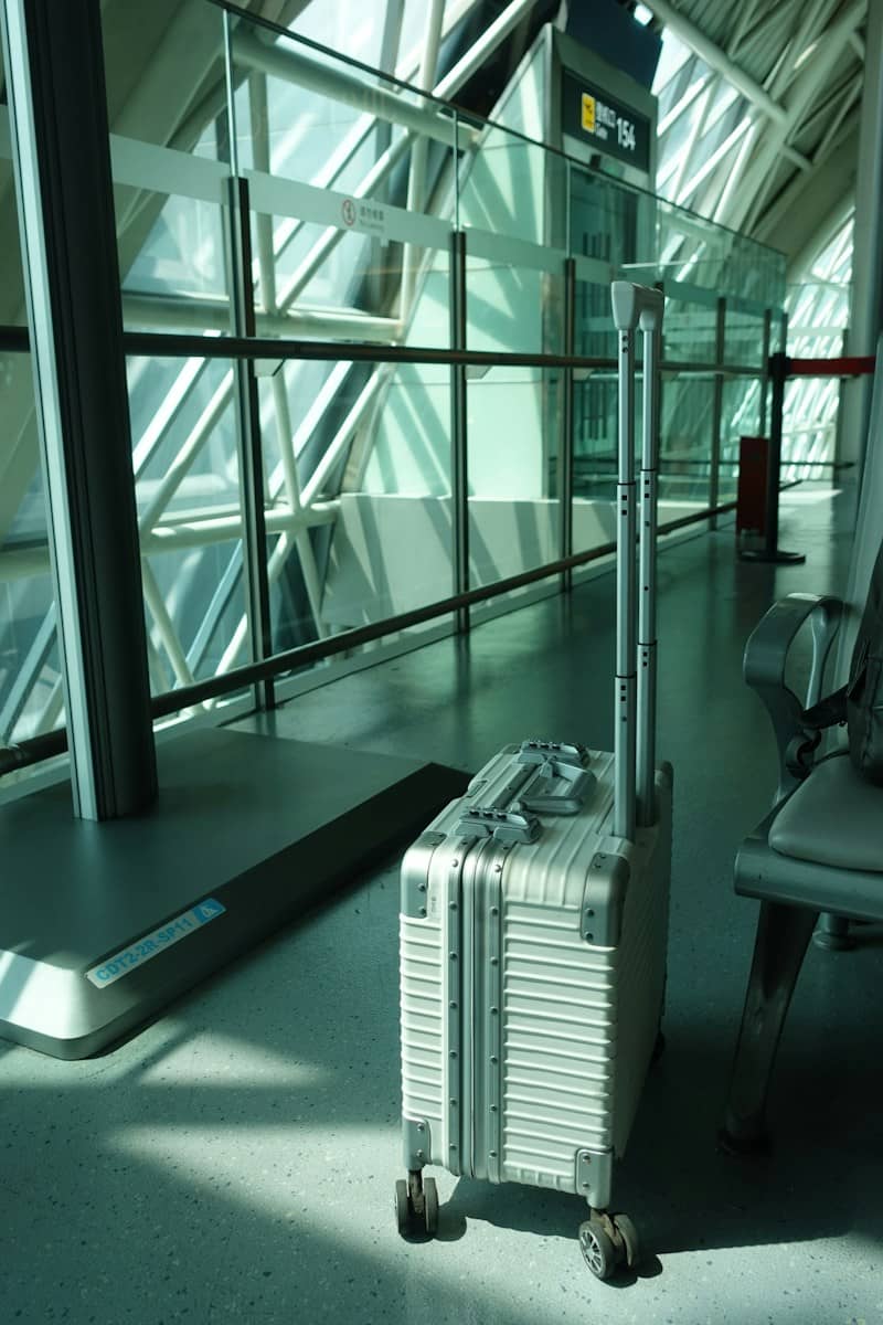 A silver suitcase with extended handle in a modern airport.