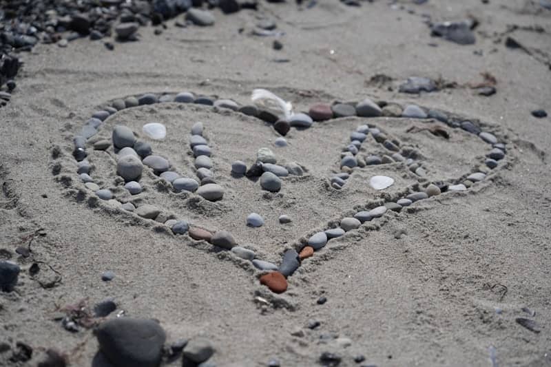 Heart shape made of pebbles on sandy beach