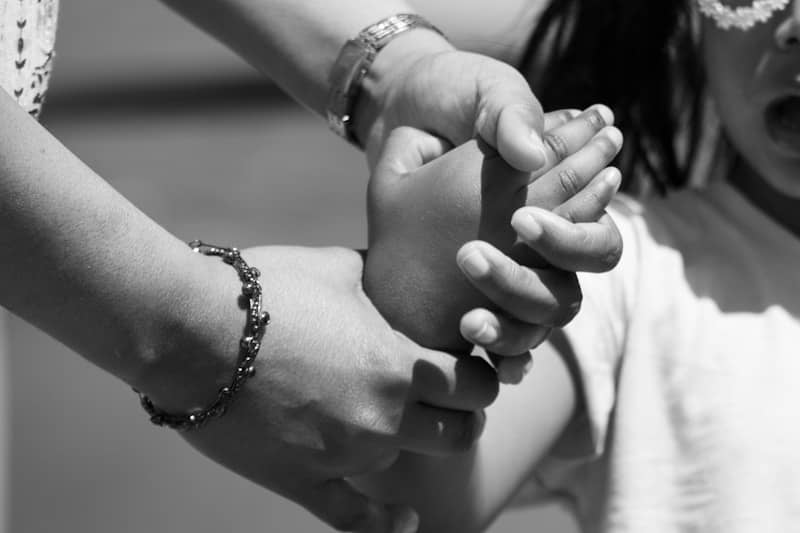 Adult hand holding a child's arm, black and white