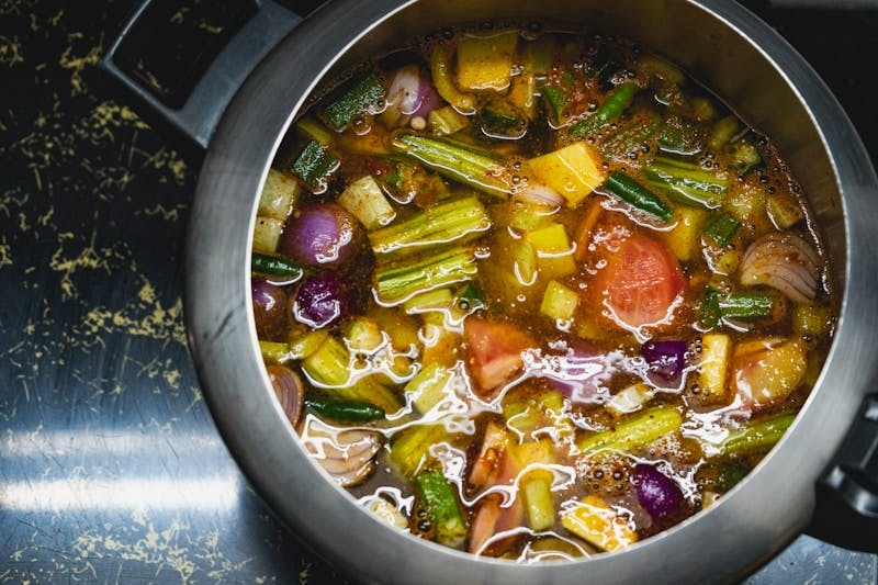 A pot of vegetable soup sitting on a stove top