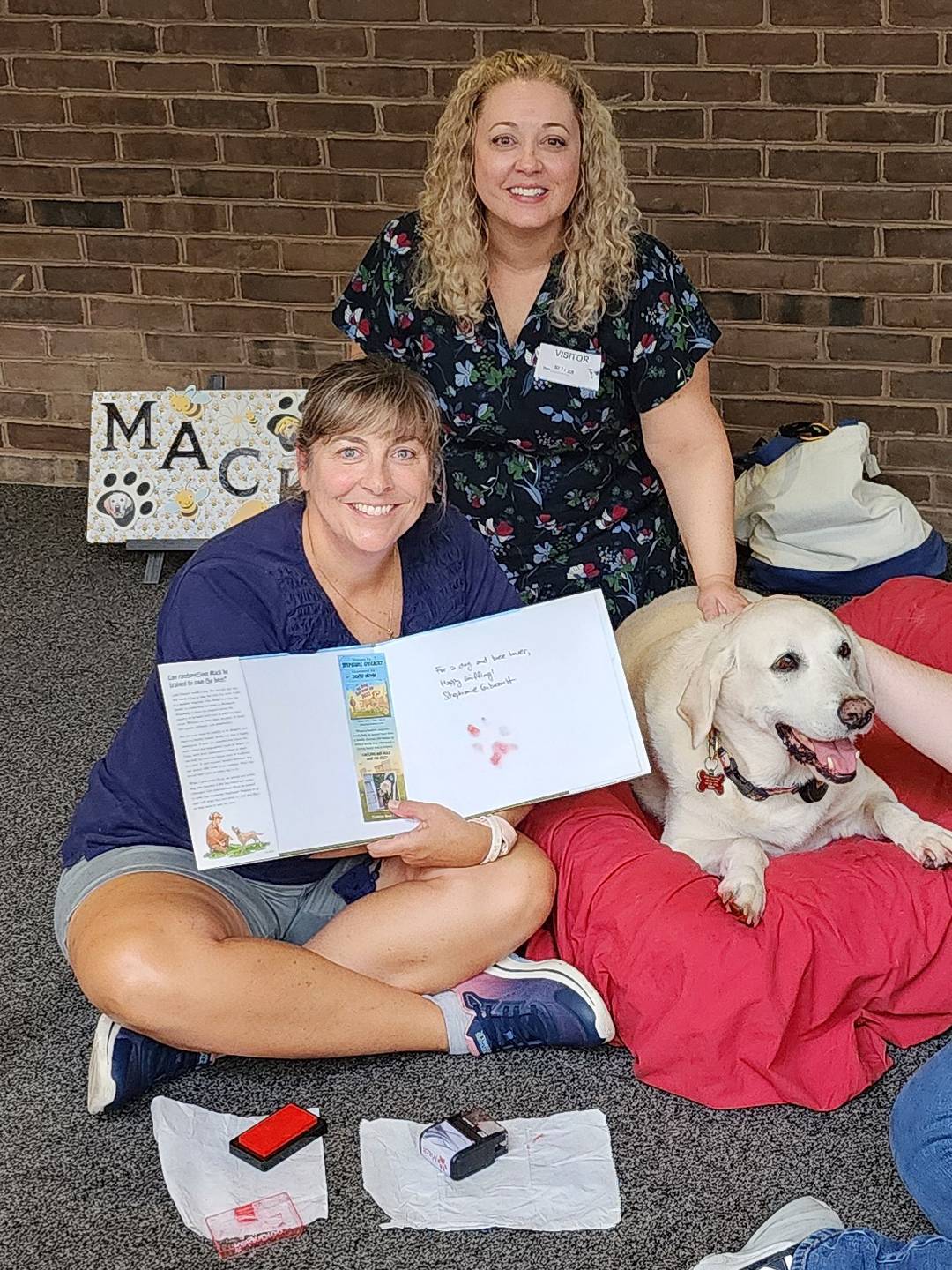 two people and a dog, one person is holding up a book