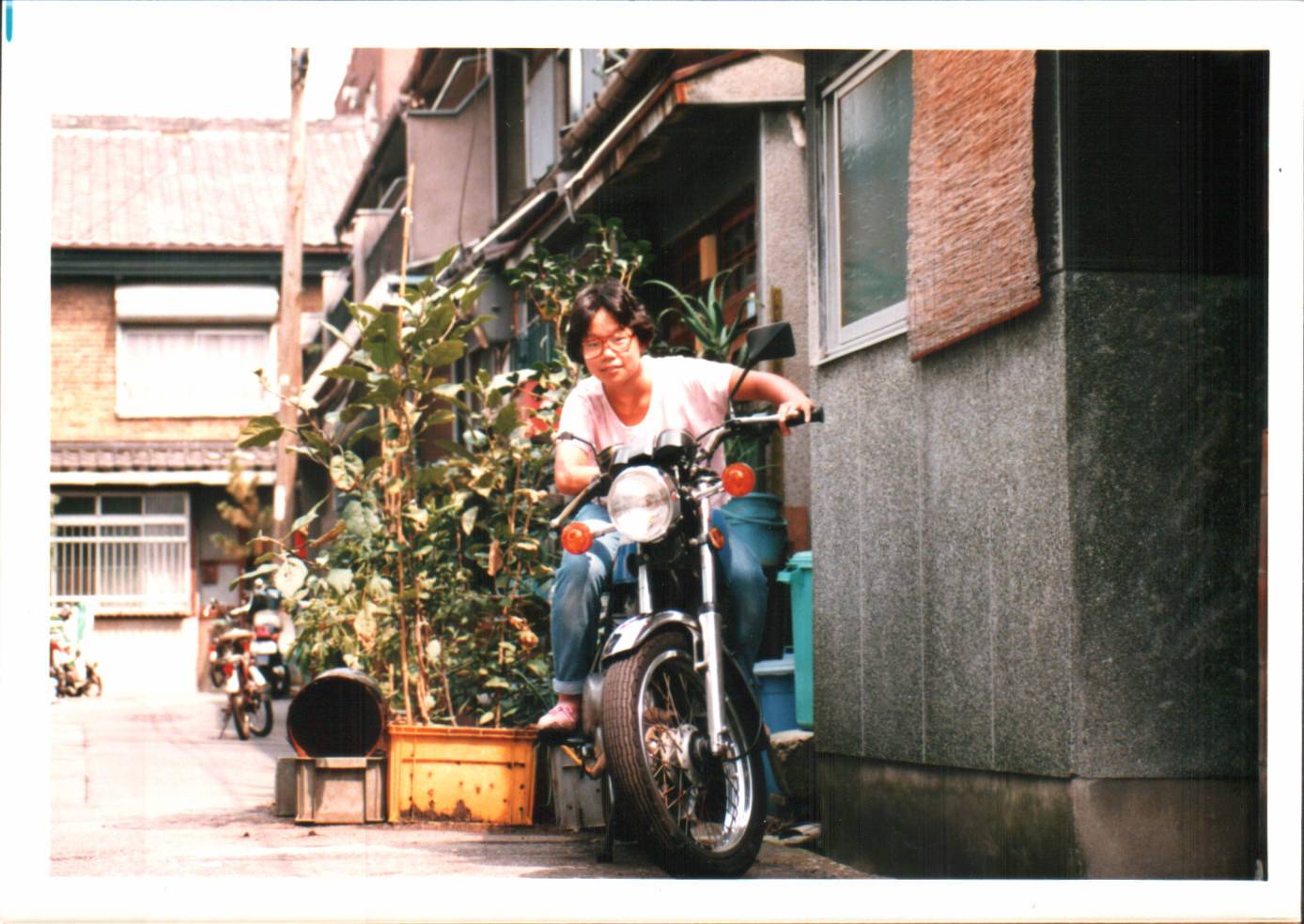 A teenage Asian girl with a big pair of glasses sitting on a motorcycle