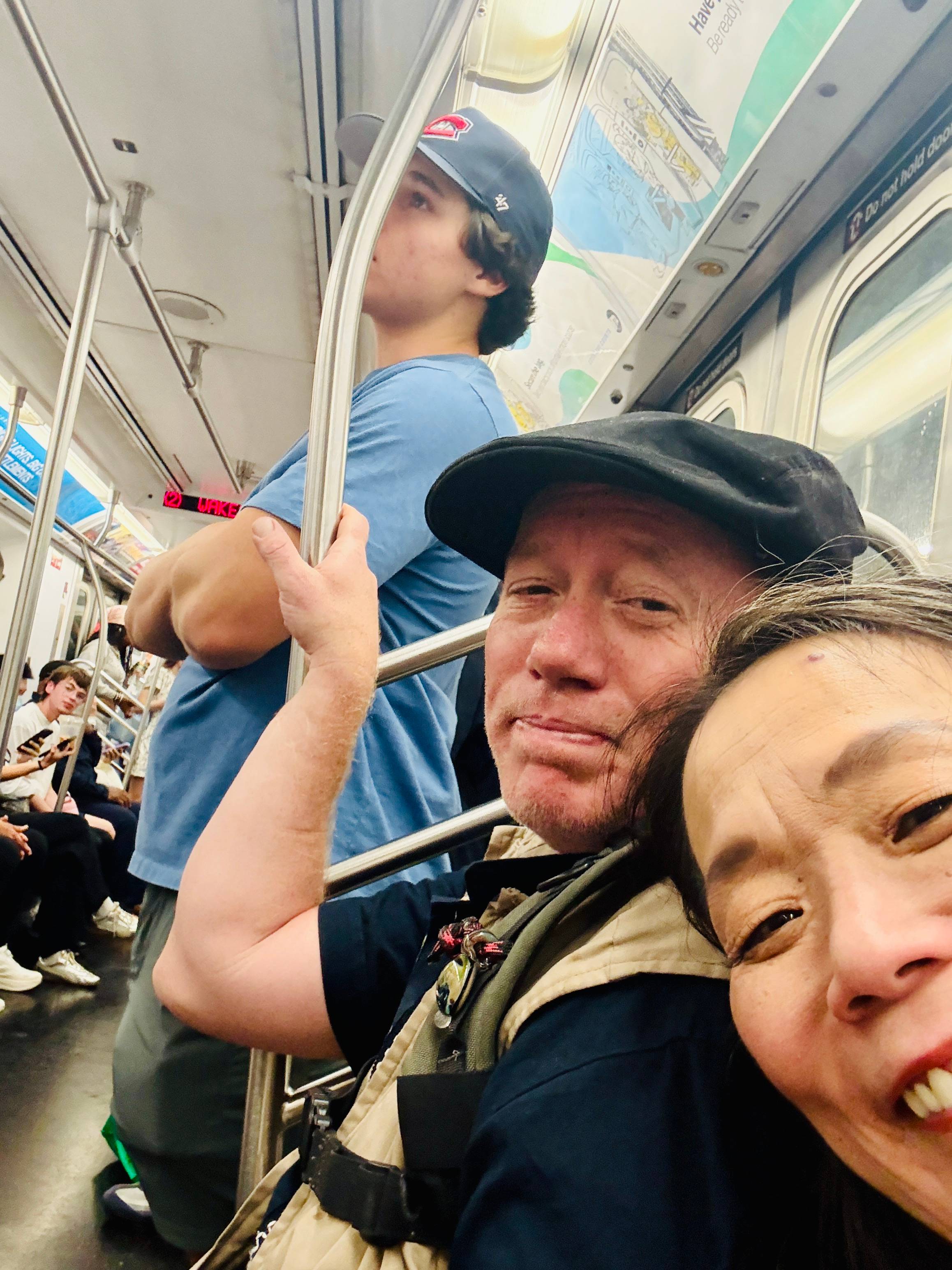 Aric and Yukari on a crowded New York City subway car, heading to Harlem.