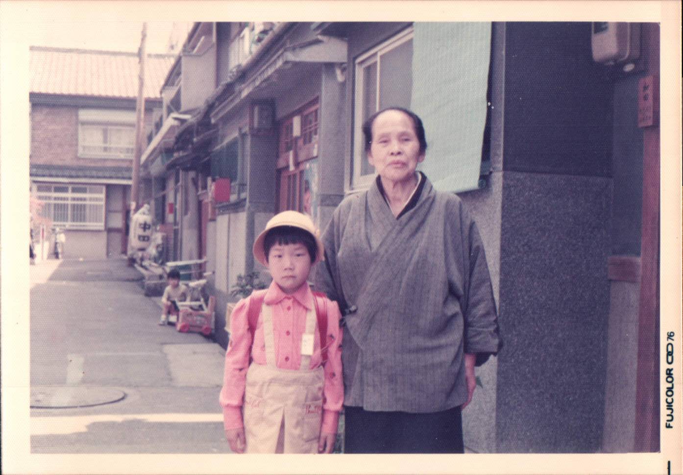 A young girl with yellow hat with pink shirt next to her grandma with kimono