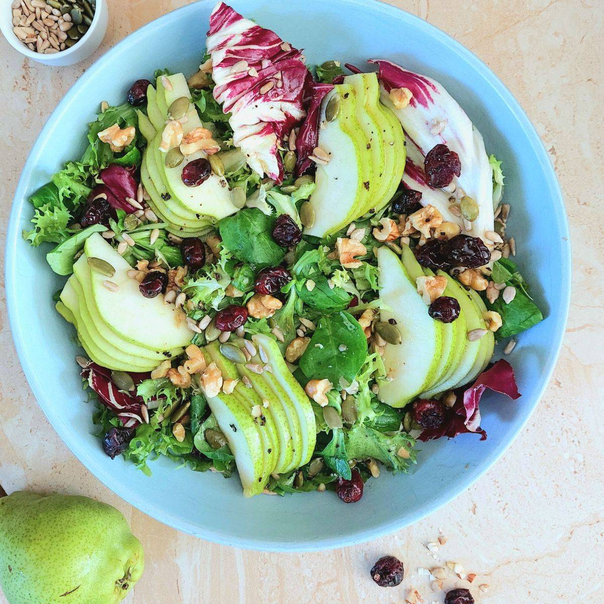 blue bowl of pear walnut cranberry salad placed on a brown granite.