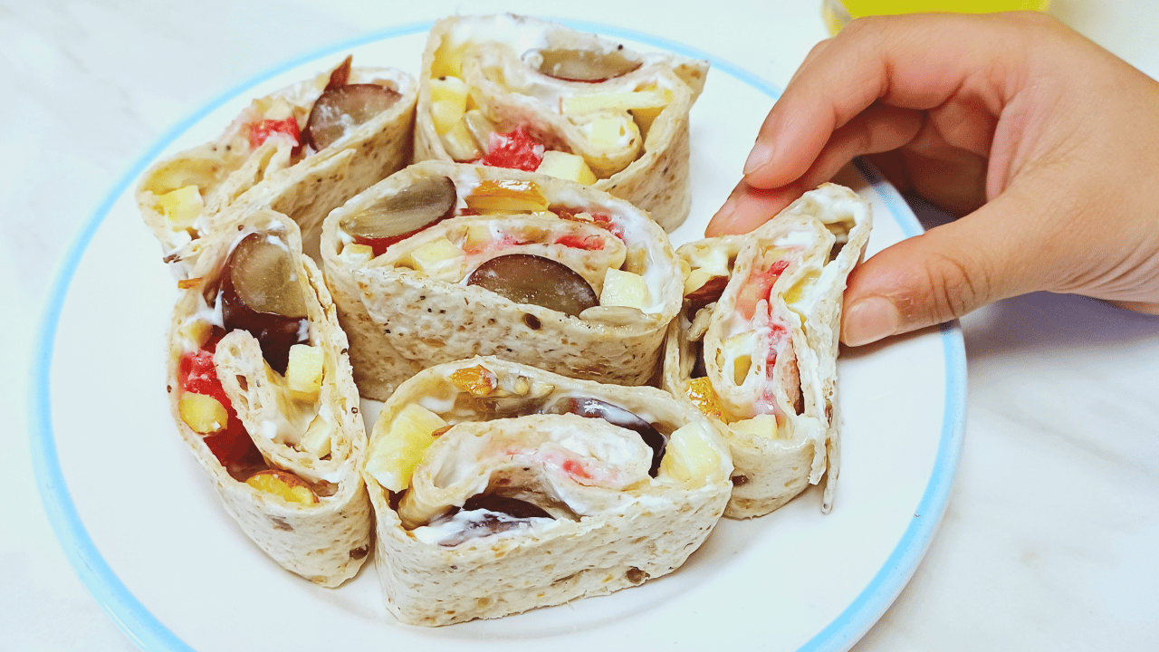 child picking tortilla fruit pinwheels from a plate.