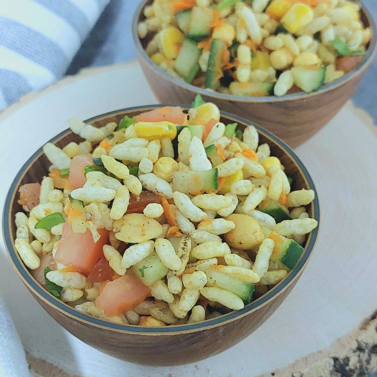 wooden bowl of puffed rice vegetable salad on wooden board.