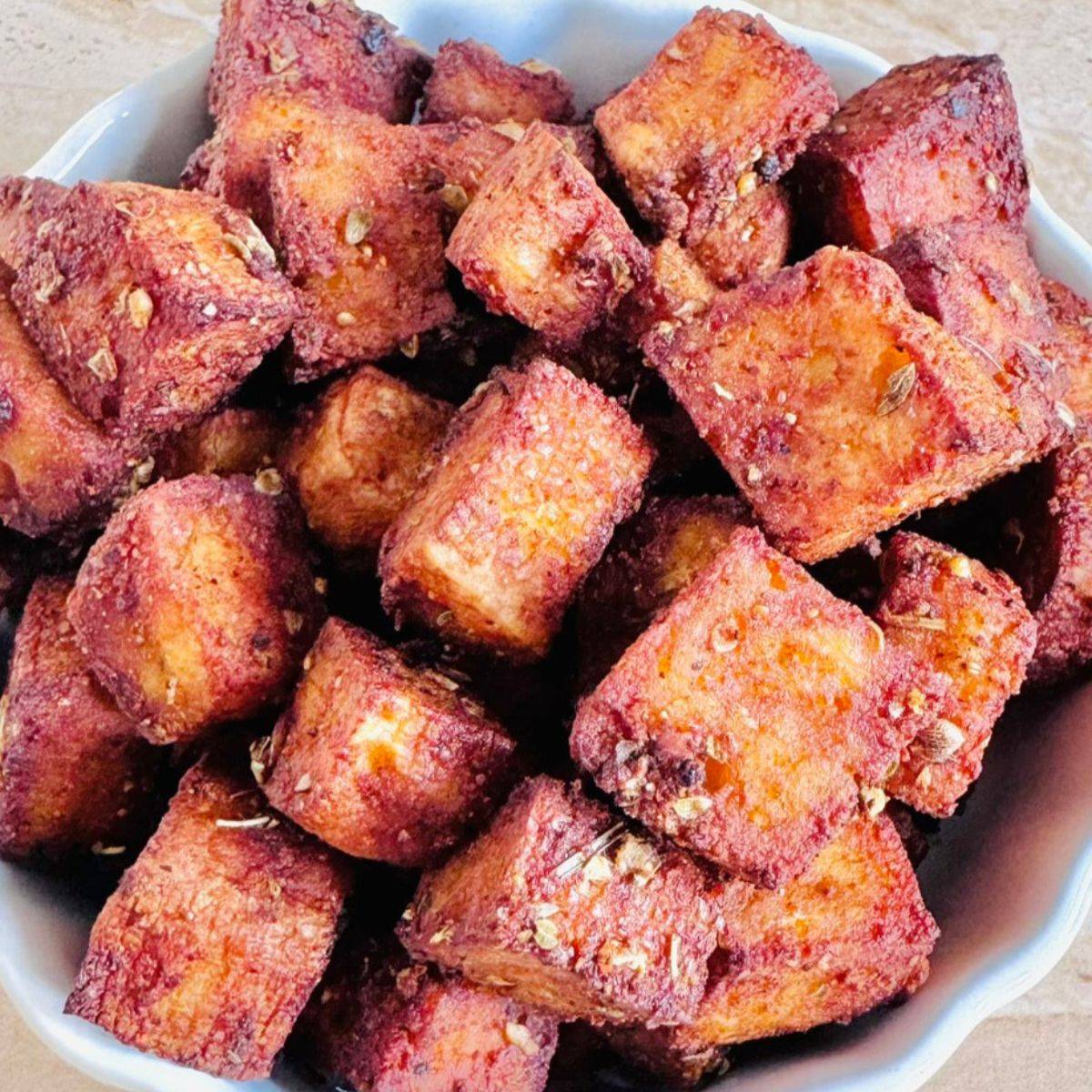close up shot of a white bowl filled with crispy baked tofu without flour. 