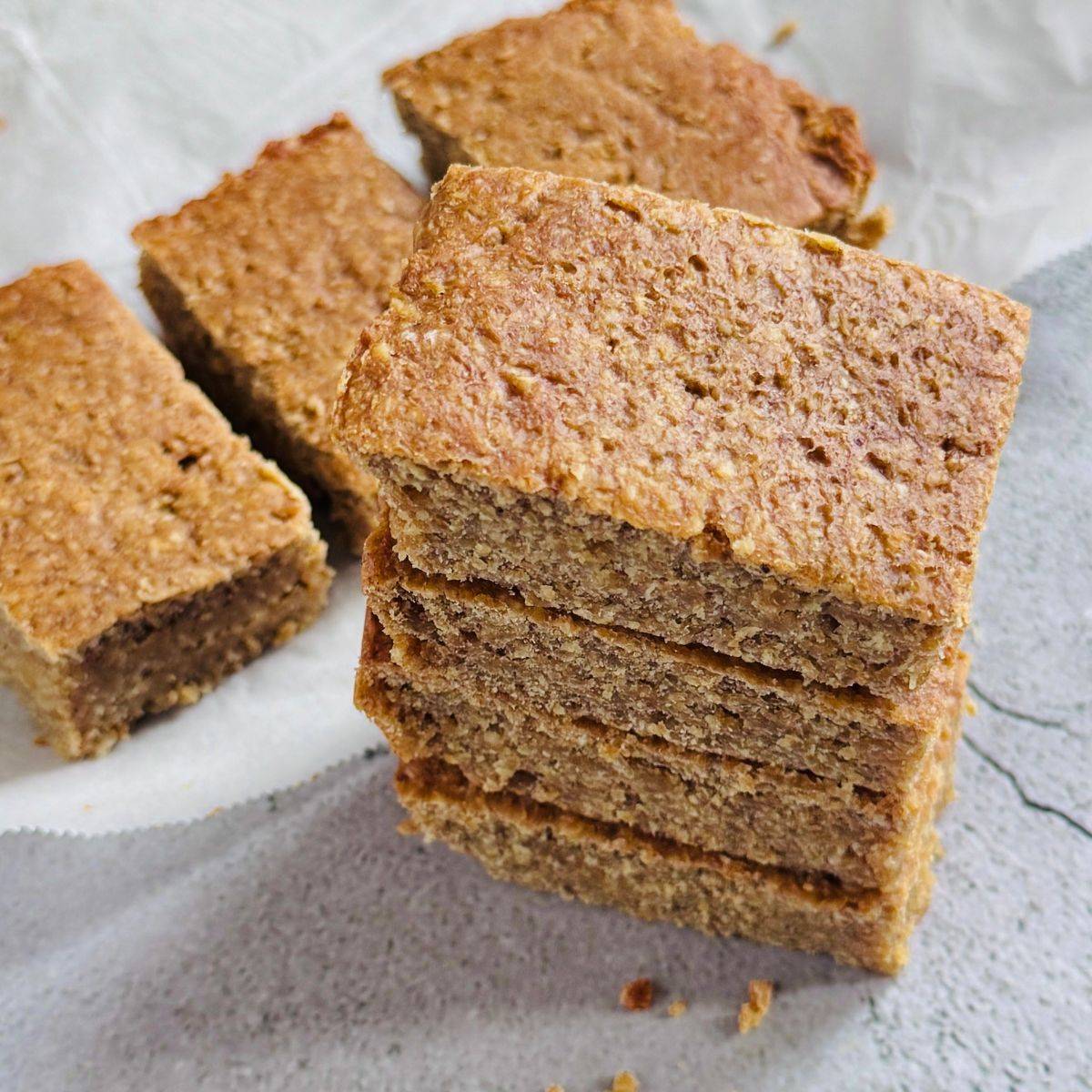 stack of banana oat bars placed on granite along with more oat bars behind them.