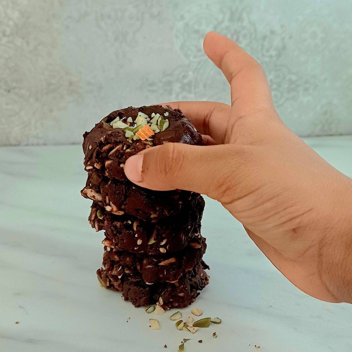 child holding a chocolate super seed bites from stack of them.