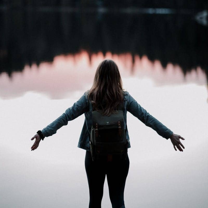 woman standing while facing on body of water