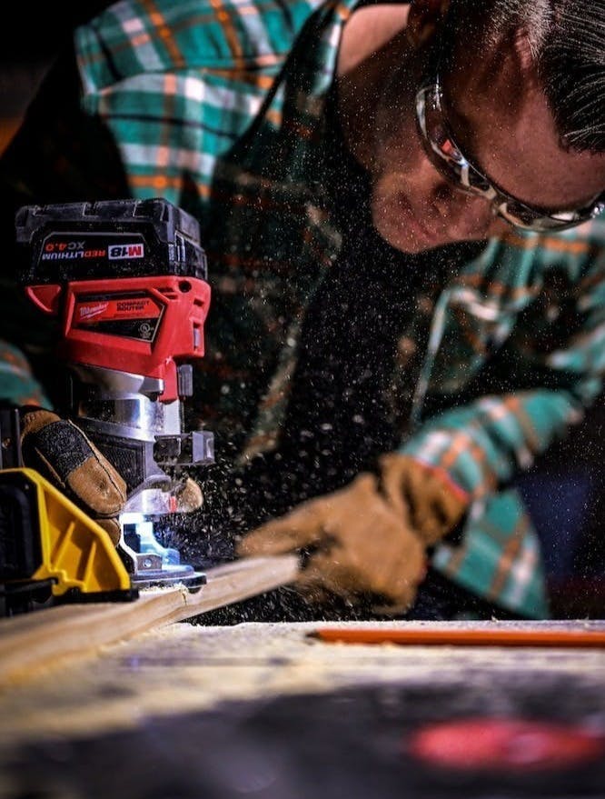 man in green and black plaid long sleeve shirt holding red and black cordless hand drill