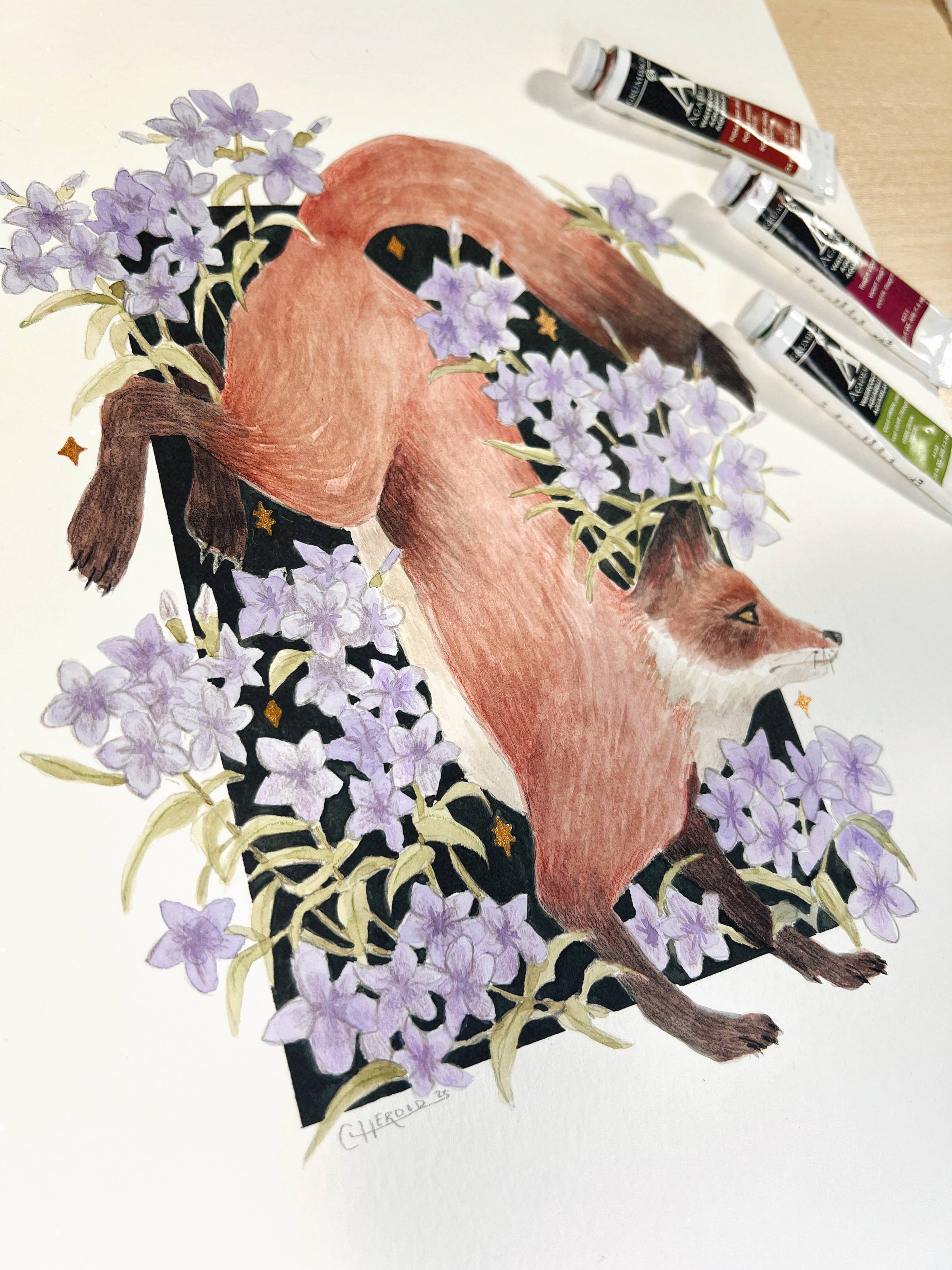 a watercolor painting of a red fox and purple phlox flowers . tubes of watercolor paint are next to the image.