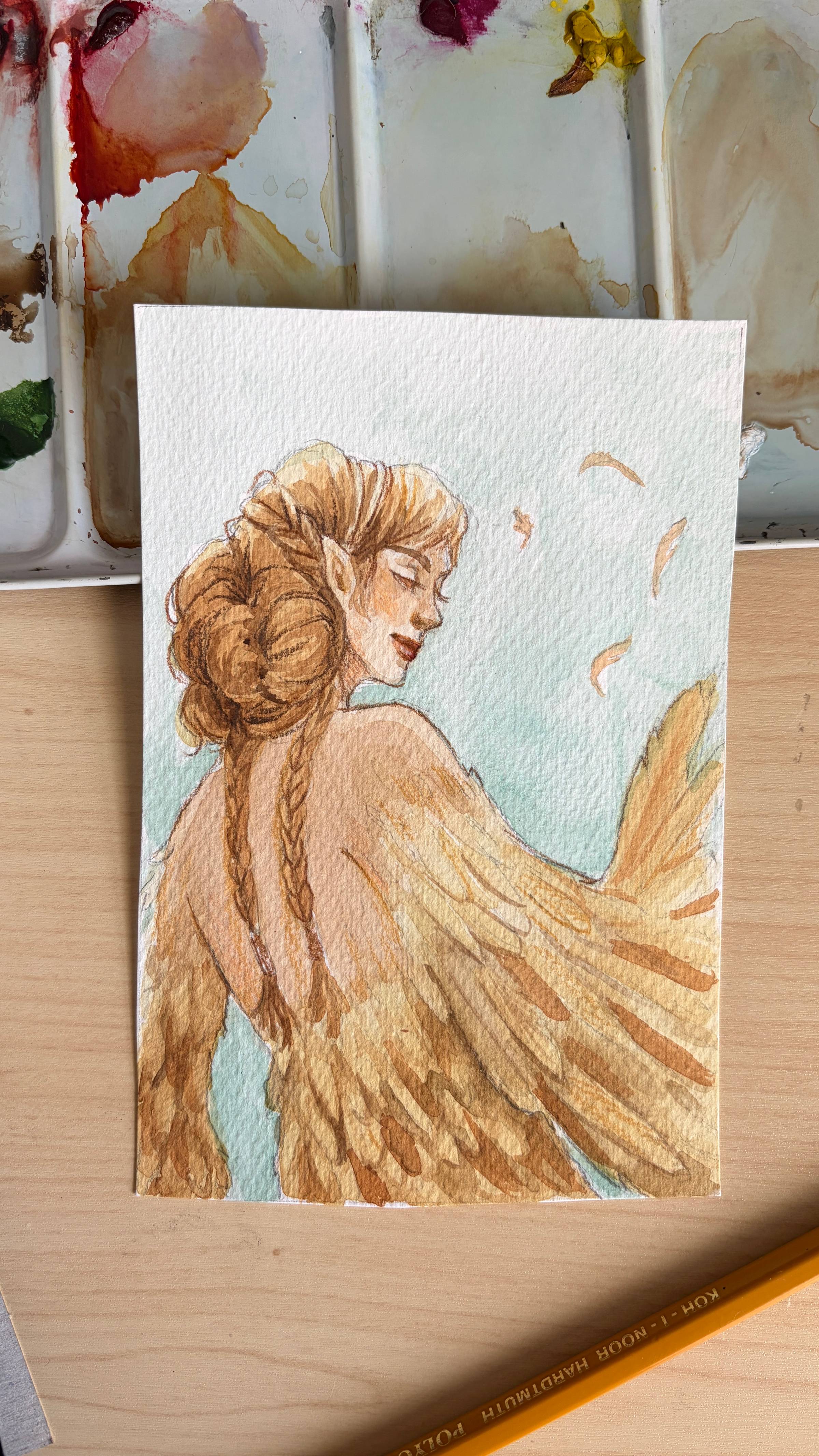 A watercolor painting of a harpy woman. The painting rests on an open metal watercolor palette.