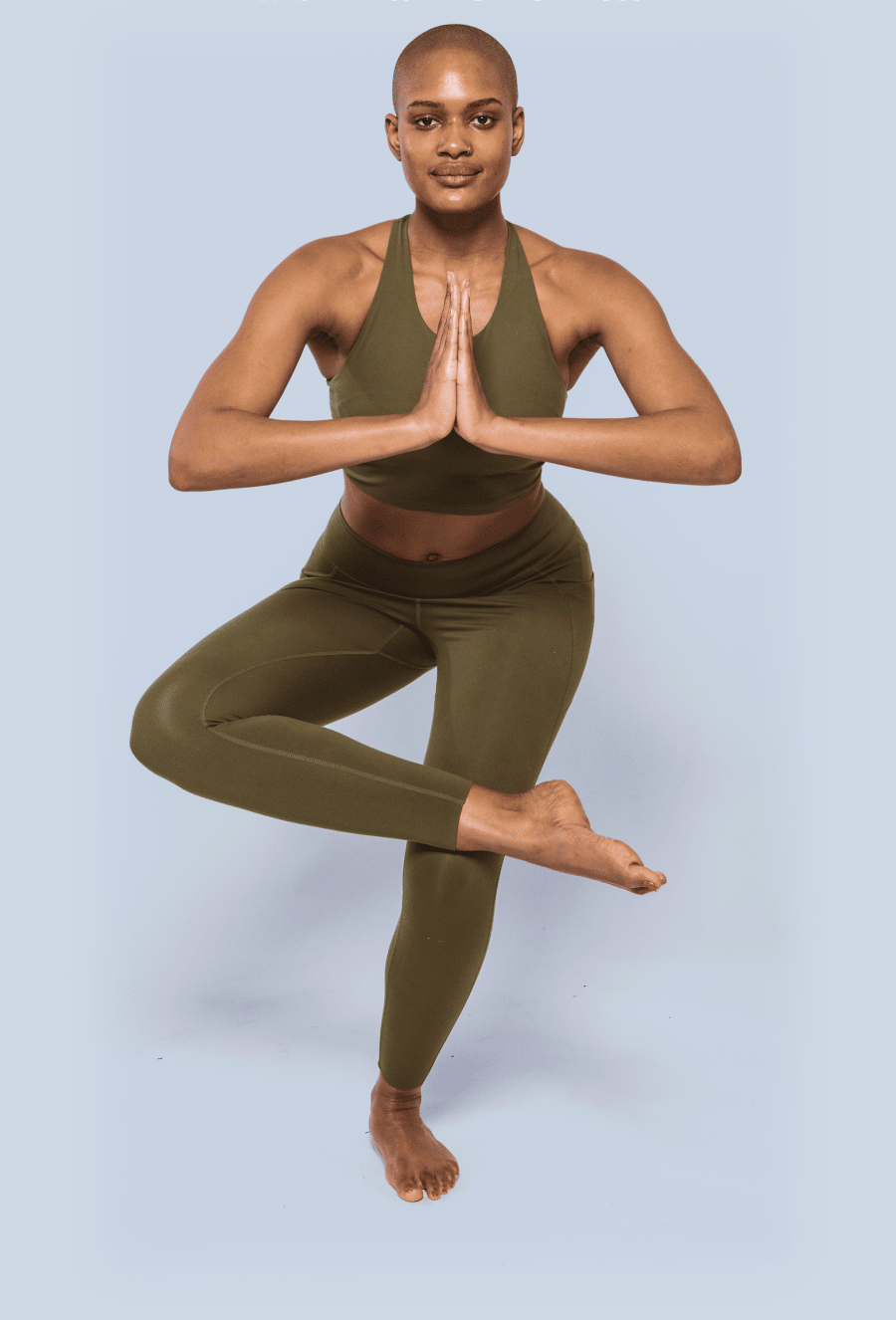 Black woman holding yoga pose in green athletic wear