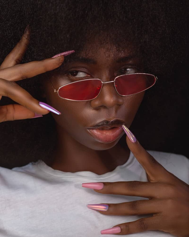 Woman with large afro and red sunglasses poses.