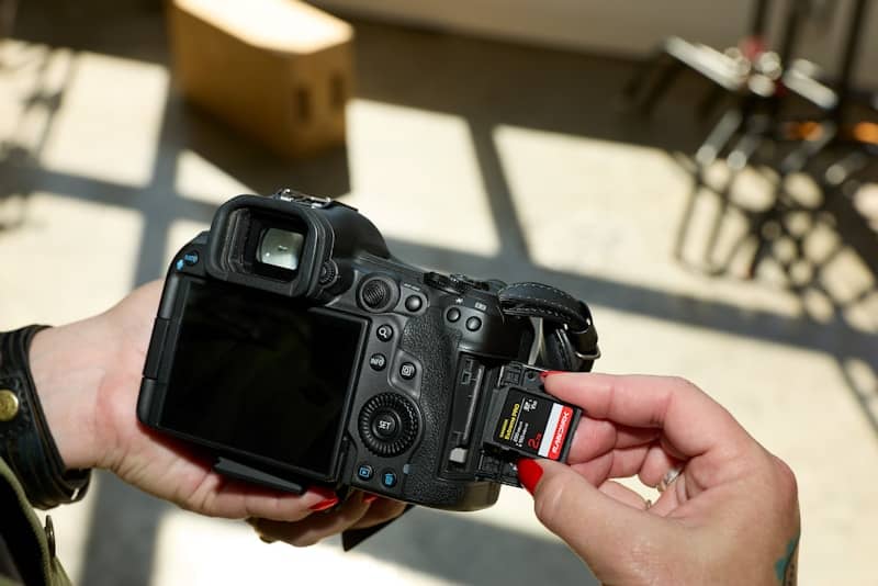 Hands inserting a memory card into a black dslr camera