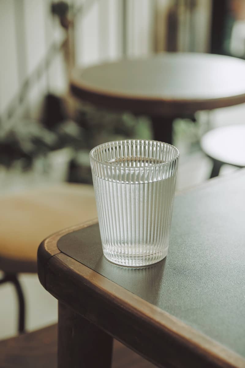A ribbed glass of water on a dark table in a cafe