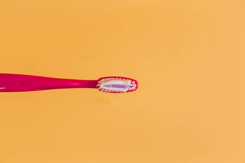 pink and yellow toothbrush on orange background