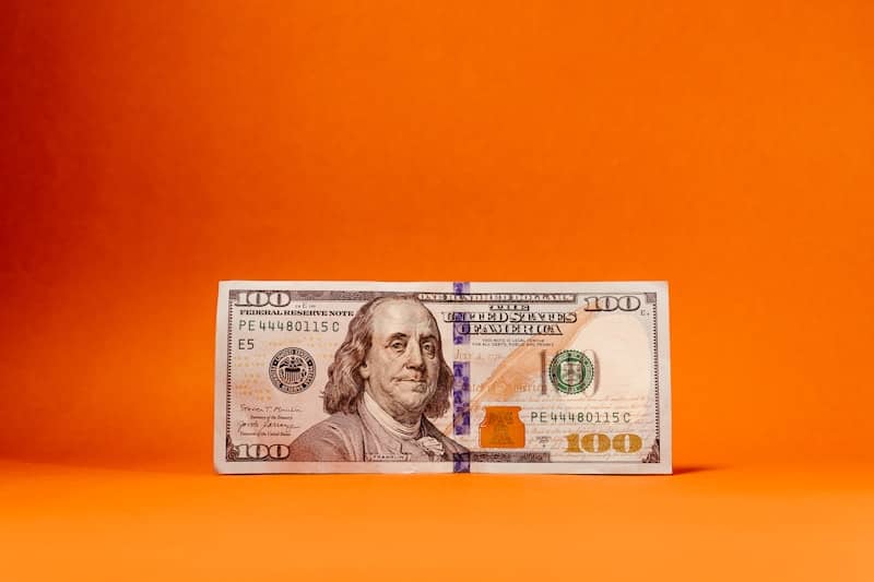 a one hundred dollar bill on an orange background