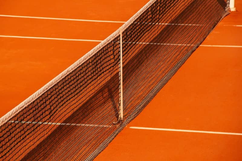 Tennis court net and lines in the sunlight.