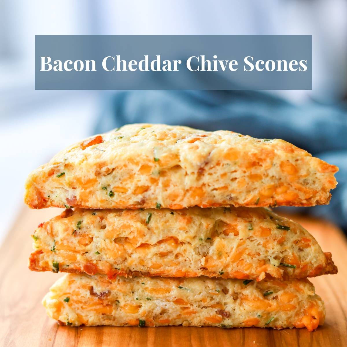 Stack of three bacon cheddar chive scones on a wood board.