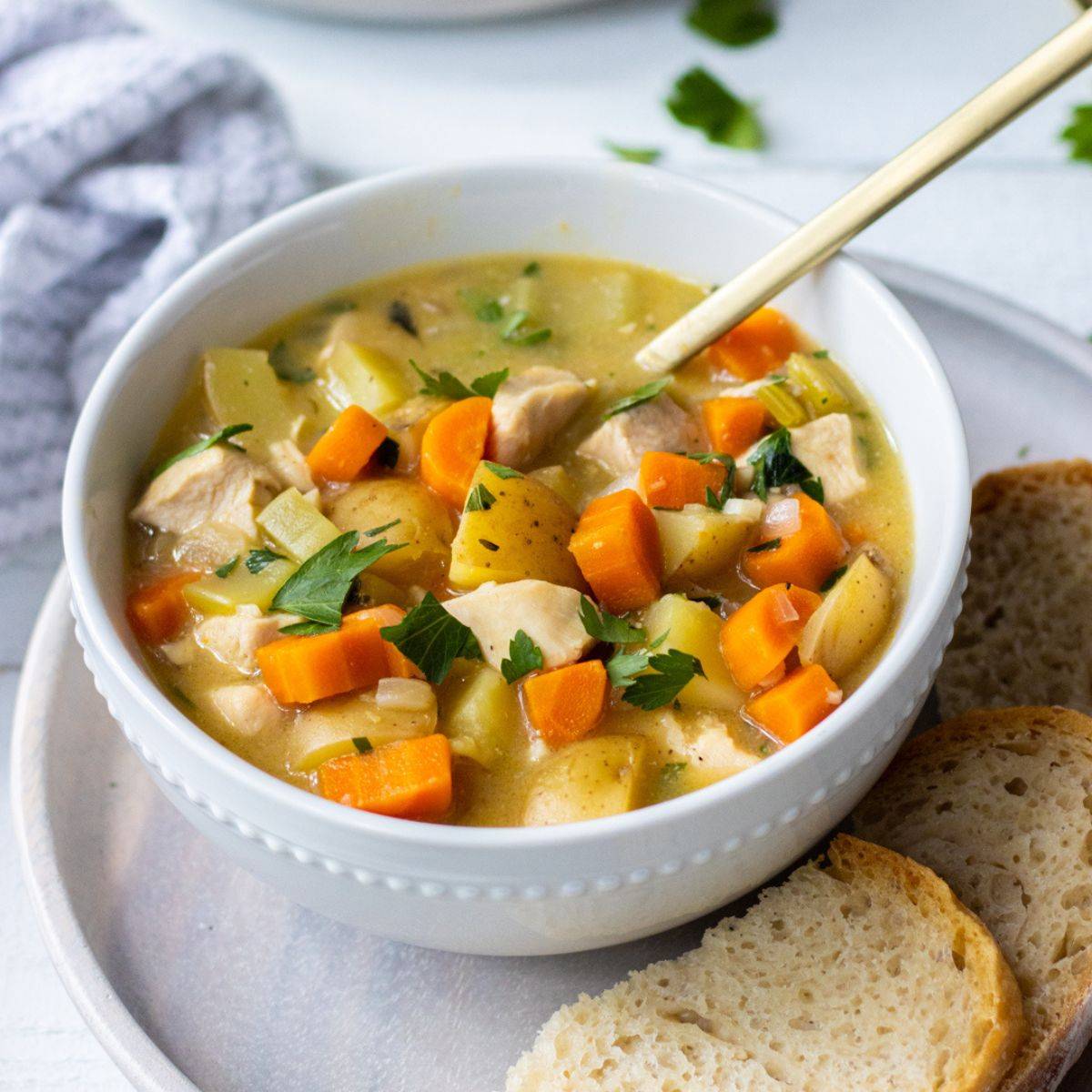 Bowl of chicken stew with slices of bread.