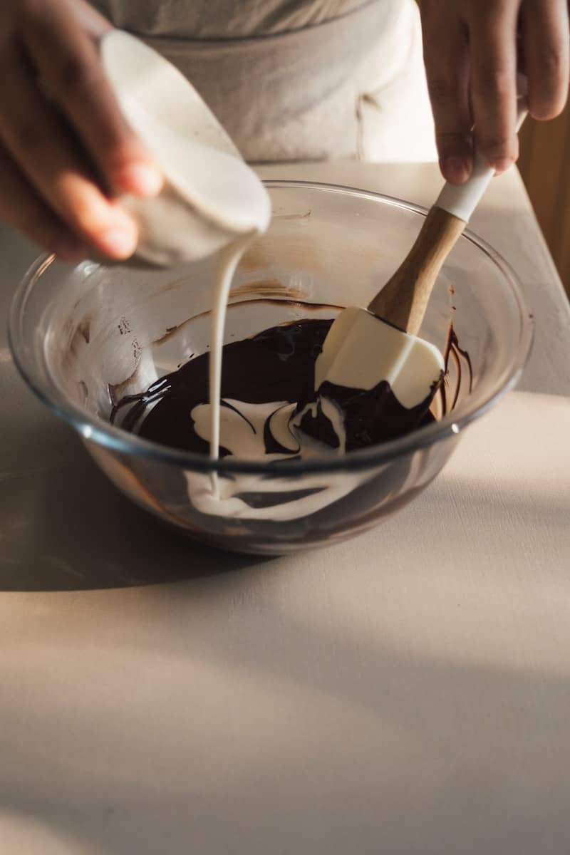 Cream being poured into melted chocolate in a bowl