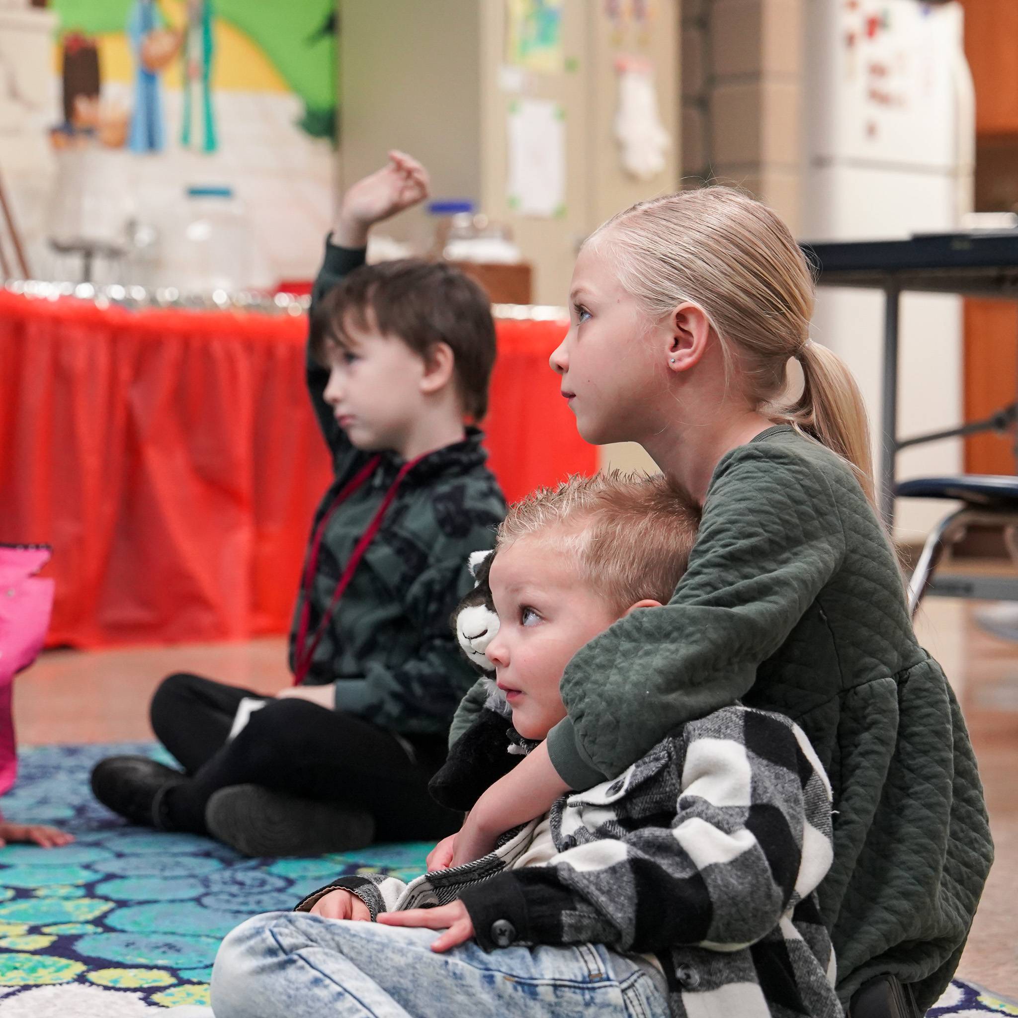 Children hugging each other in a classroom setting. 
